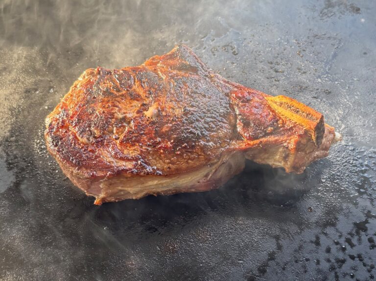 Bone-in ribeye searing on a hot griddle