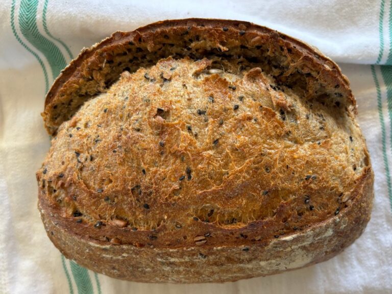 Seeded sourdough loaf on a striped kitchen towel
